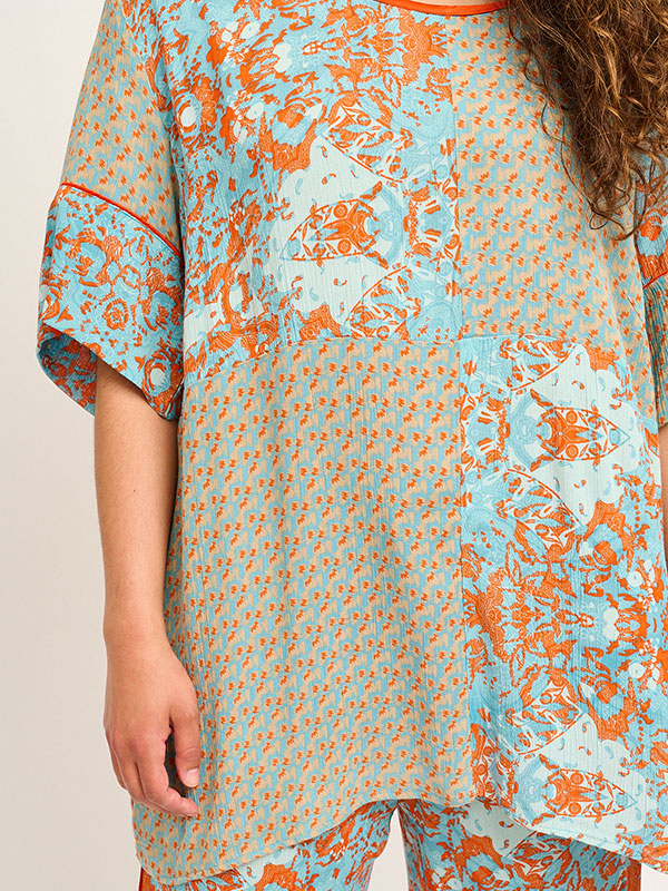 Blå bluse i crepet viskose med sand og orange mønster fra Adia