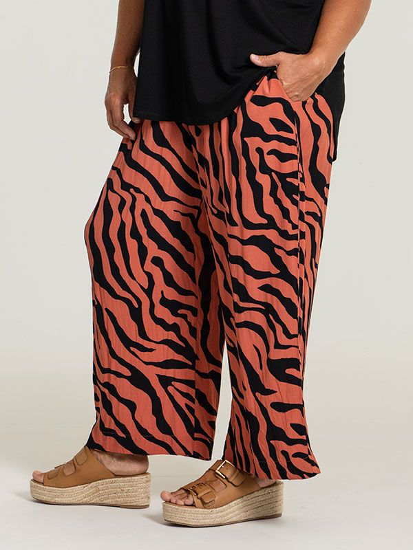ELLY - Løse orange bukser med sort print fra Gozzip